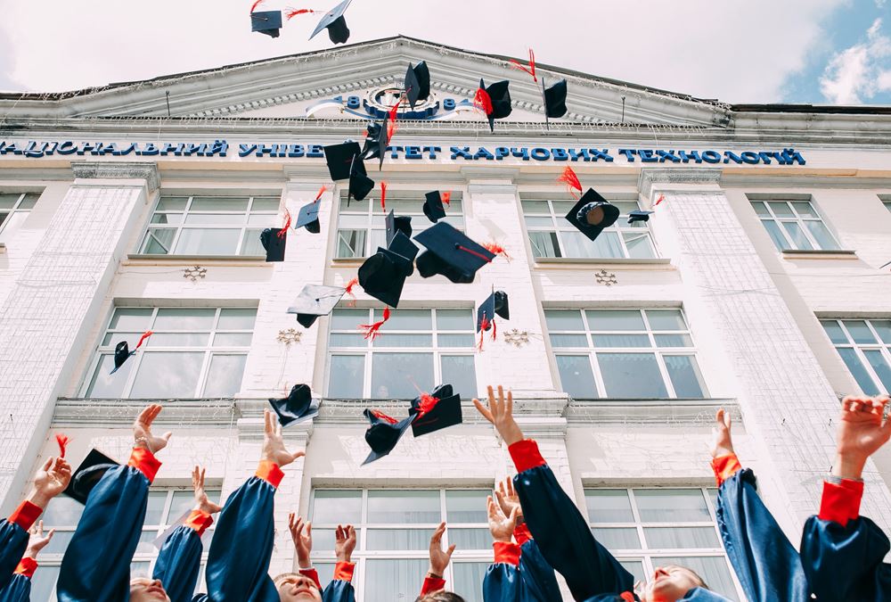 Graduates throwing their caps outside an education institution